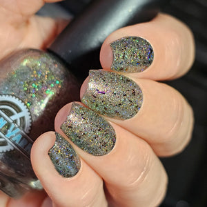 Victorian Varnish continues their 'Apotheker Peculiarities' with a polish inpisred by Wizarding Apotheker!

"Vulcanized" has a grey base with bronze/green/gold multichromatic shimmer and iridescent purple to green large particle shimmer, scattered holo, UCC flakies and black reflective glitters.