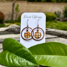 Bernd Offerings continues their 'Musicals' series with a pair of earrings inspired by The Wizard Of Oz!

These charming earrings feature an antique copper hammered circle framing a natural shell coin bead—each one uniquely patterned, making every pair one-of-a-kind. An iridescent faceted glass bead adds just the right touch of sparkle while antique copper plated ear wires and silicone backs provide a comfortable fit. Earrings measure just over 1¾" long.