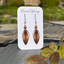 Celebrate the magic of the season with these whimsical, handcrafted mixed metal earrings! A rustic antique copper leaf is framed by a silver-plated oval, hand-shaped to echo the leaf’s natural curve, and accented with a Czech glass matte copper round and petite metal bead. Earrings measure 2.5" long with uniquely curved stainless steel ear wires and silicone backs.