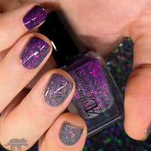 The second in a series inspired by Alchemy from Alchemy Lacquers, “Magical Transmutation” is a solar nail lacquer that shifts from a mid-toned gray in the shade to various shades of purple in the sun, with pink to orange to gold shifting iridescent flakes and a touch of black metallic flakes.&nbsp;