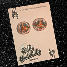 Golly Oodelally Designs rings in the holidays with the "Tis the Season to Read More Books" Acrylic Earrings.

Each earring measures 1 inch by 1 inch.