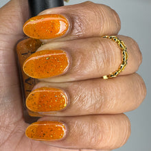 "Don't Leave Me Alone In This World" is a jelly orange polish with gold/pink matallic flakes and shimmers of red and gold.

15ml Bottle